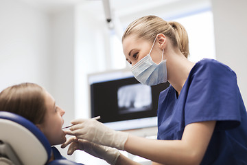 Image showing female dentist checking patient girl teeth