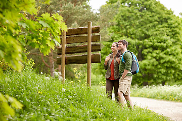 Image showing smiling couple at signpost with backpacks hiking