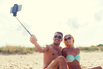 Image showing happy couple in swimwear sitting on summer beach