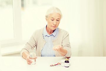 Image showing senior woman with water and medicine at home