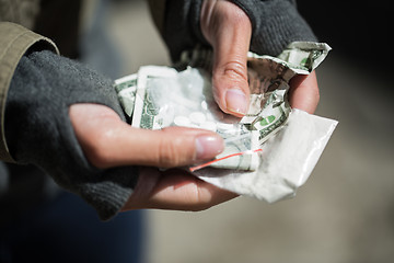Image showing close up of addict hands with drugs and money
