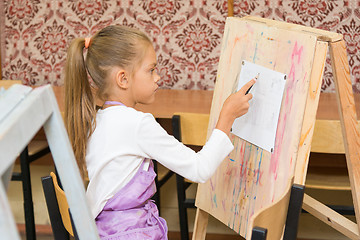 Image showing Girl paints on an easel in the drawing lesson