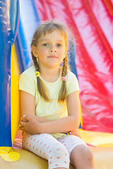 Image showing Five-year girl naprygalis on a large inflatable trampoline sat down to rest