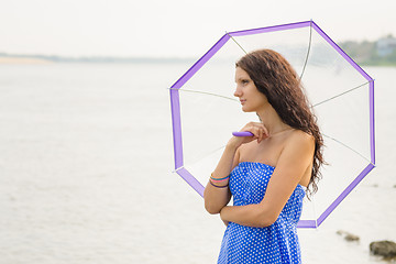 Image showing Happy young girl standing with an umbrella on a background of a morning river