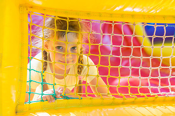 Image showing A five-year girl is looking through a mesh trampoline inflatable