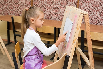 Image showing Girl artist paints on an easel to draw circle