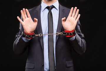 Image showing man in a business suit with leather bound with handcuffs. sex Toys