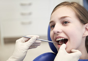 Image showing hands with dental mirror checking girl teeth