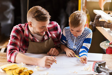 Image showing happy father and son with blueprint at workshop