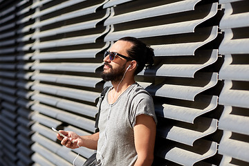 Image showing man with earphones and smartphone on city street