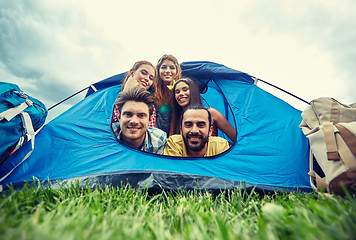 Image showing happy friends with backpacks in tent at camping