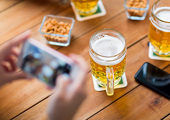 Image showing close up of hands with smartphone picturing beer