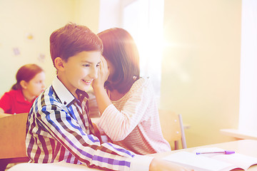 Image showing smiling schoolgirl whispering to classmate ear