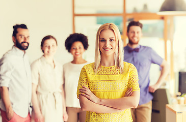 Image showing happy young woman over creative team in office