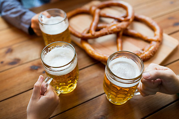 Image showing close up of hands with beer mugs at bar or pub