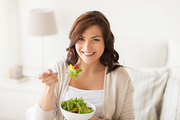 Image showing smiling young woman eating salad at home