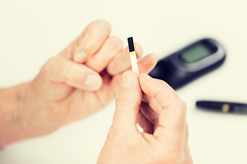 Image showing senior woman with glucometer checking blood sugar