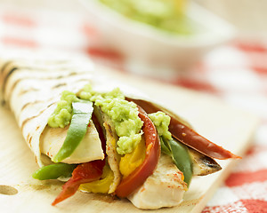 Image showing delicious wrap tortilla with spicy chicken vegetables guacamole