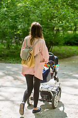 Image showing Happy mother walking with baby stroller in park