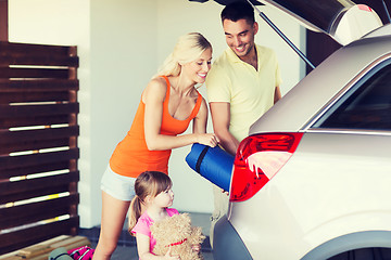 Image showing happy family packing things to car at home parking