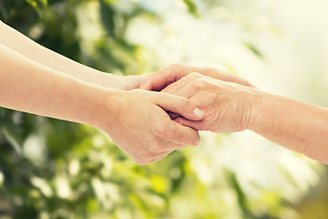 Image showing close up of senior and young woman holding hands