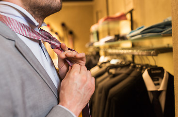 Image showing close up of man tying tie at clothing store mirror