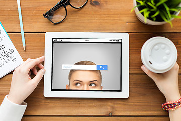 Image showing close up of woman with tablet pc on wooden table