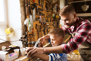 Image showing father and son with plane shaving wood at workshop