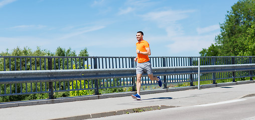 Image showing smiling young man running at summer seaside