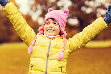 Image showing happy little girl with raised hands outdoors