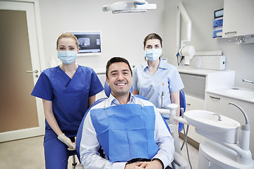 Image showing happy female dentists with man patient at clinic