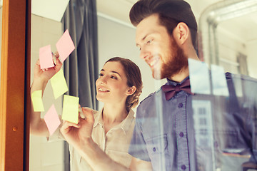 Image showing happy creative team writing on stickers at office