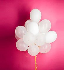 Image showing close up of white helium balloons over pink