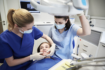 Image showing happy female dentist with patient girl at clinic