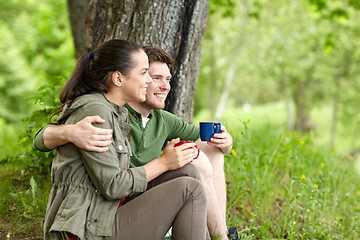 Image showing happy couple with cups drinking tea in nature