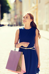 Image showing happy woman with shopping bags walking in city 