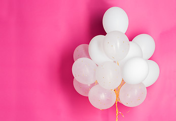 Image showing close up of white helium balloons over pink