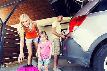 Image showing happy family packing things to car at home parking