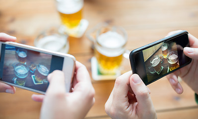 Image showing close up of hands with smartphone picturing beer