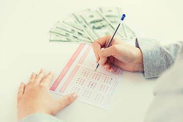 Image showing close up of hands with lottery ticket and money