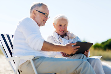 Image showing happy senior couple with tablet pc on summer beach