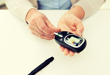 Image showing senior woman with glucometer checking blood sugar