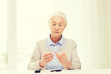 Image showing senior woman with glucometer checking blood sugar