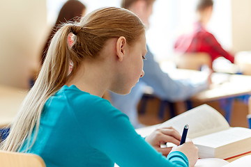 Image showing close up of student with book writing school test