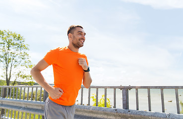 Image showing smiling young man running at summer seaside