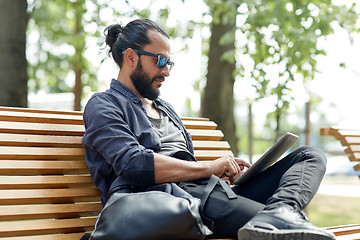 Image showing man with tablet pc sitting on city street bench