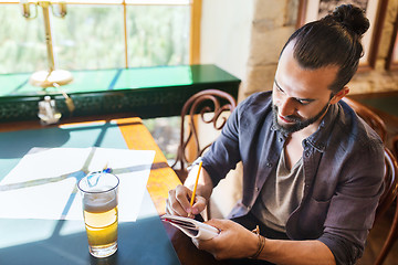 Image showing man with beer writing to notebook at bar or pub