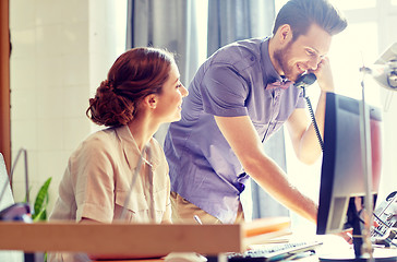 Image showing happy creative team calling on phone in office