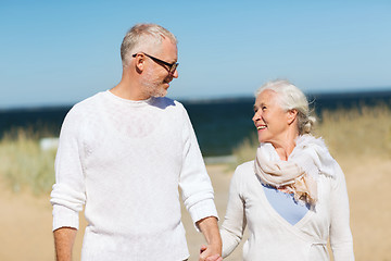 Image showing happy senior couple holding hands on summer beach