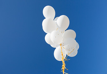 Image showing close up of white helium balloons in blue sky